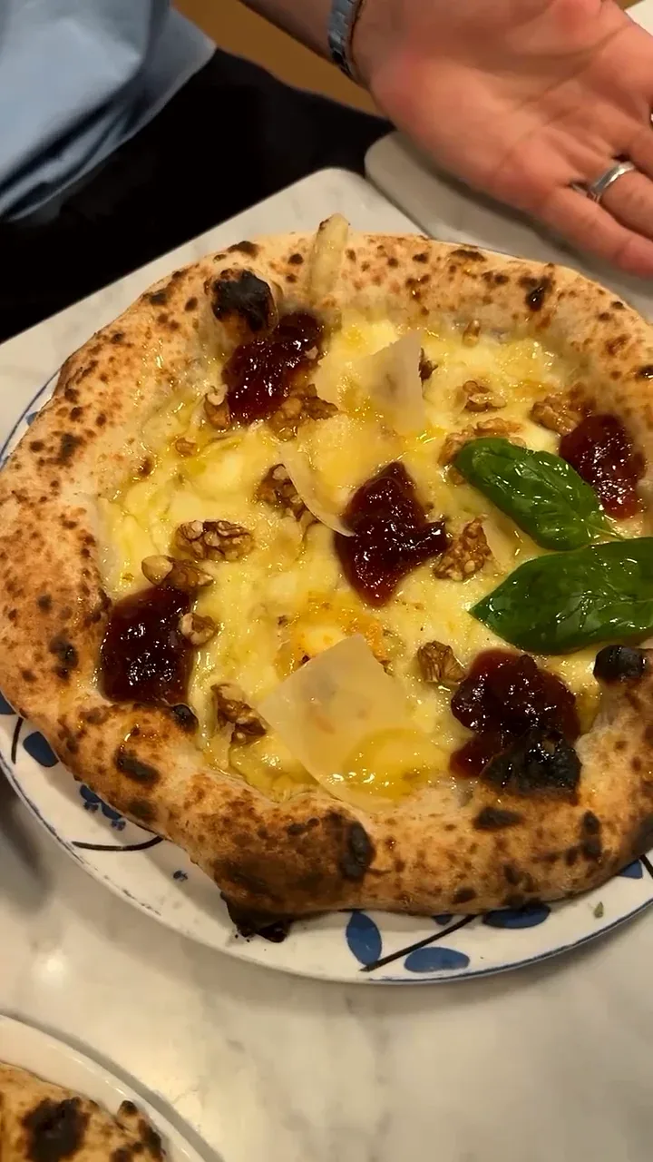Pizza garnie à la main puis servie à table